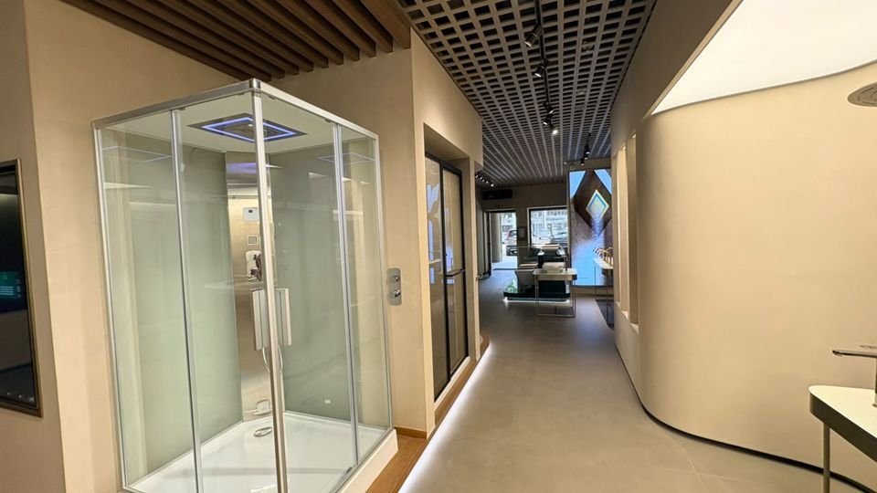 Shower enclosure. A framed glass enclosure with an illuminated overhead shower, beside a curved, uplit wall.