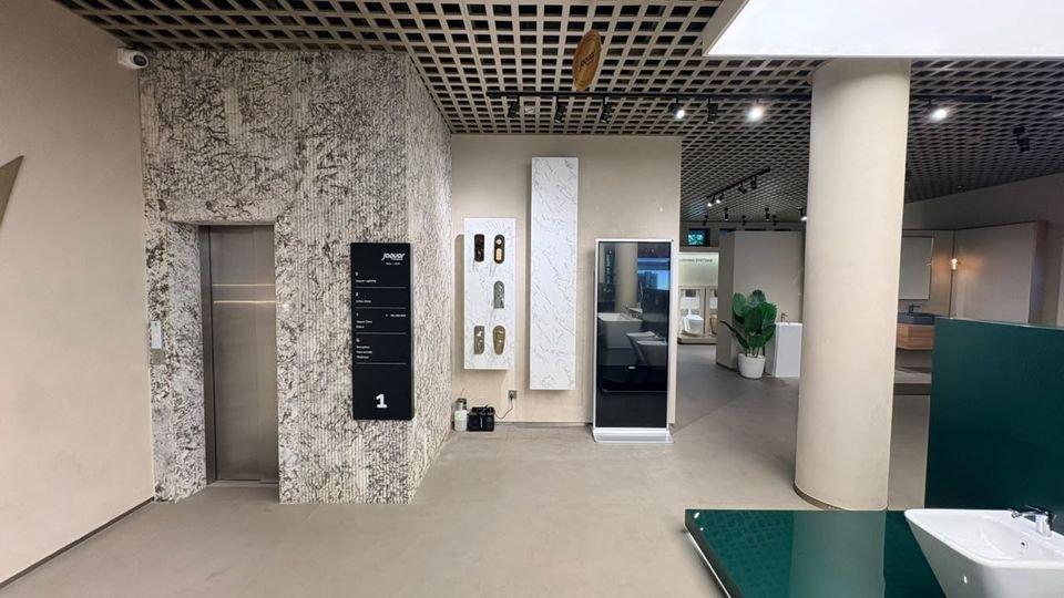 Floor 01 lift lobby. A stone-clad lift core with floor signage, finish samples and a digital display totem.