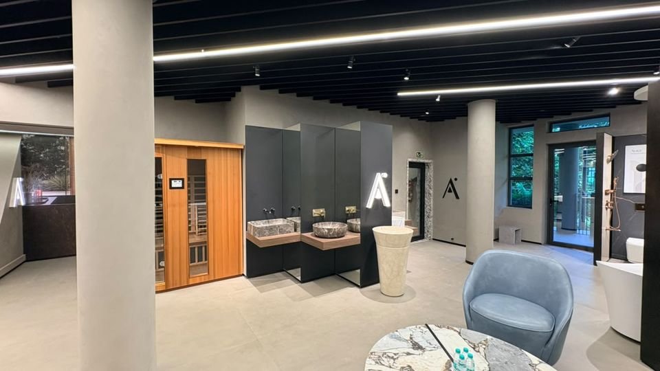 Sauna & stone basins. A timber sauna cabin, stone vessel basins on a dark wall and a pedestal basin, with Artize branding.