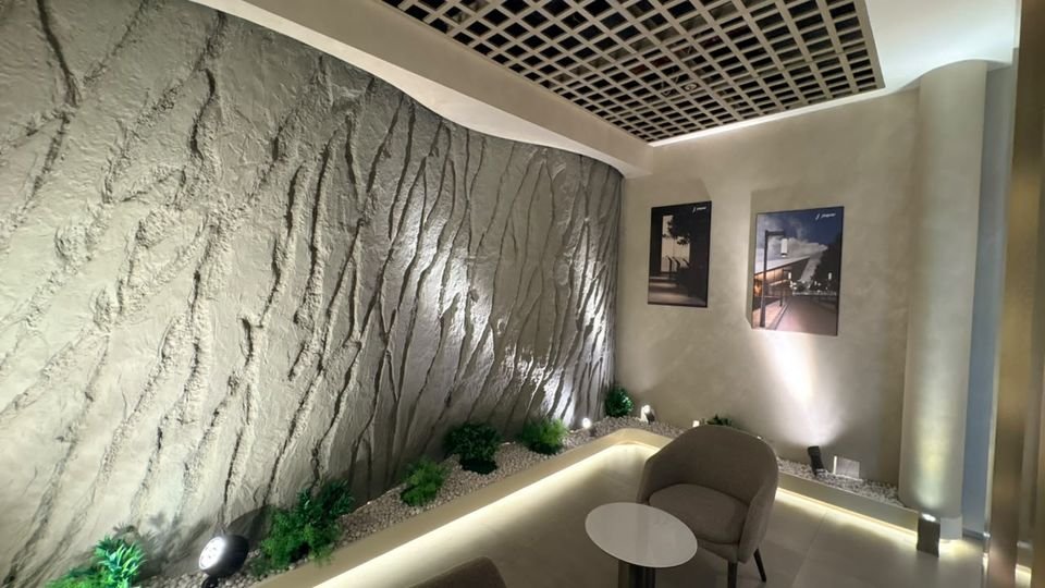 Sculpted wall grazing. Spotlights grazing a deeply textured wall above a planted, cove-lit bed.