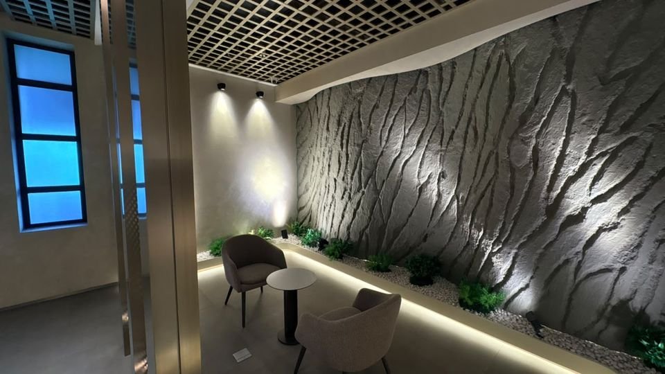 Textured wall lounge. A spotlit sculpted wall, with lounge chairs and a side table.