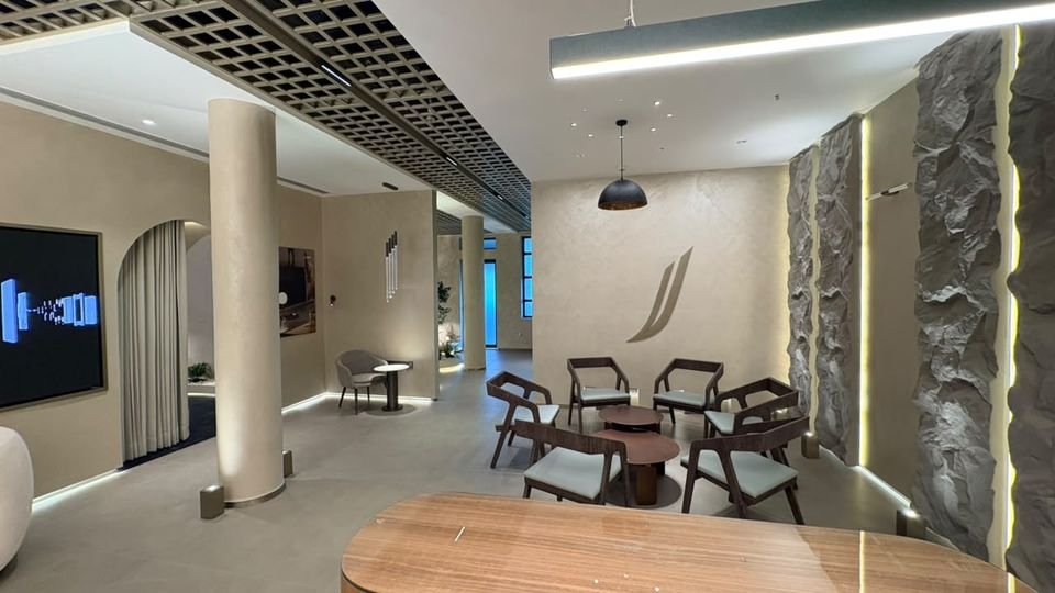Seating area. Timber chairs around low tables beside stone-clad walls with LED reveals.